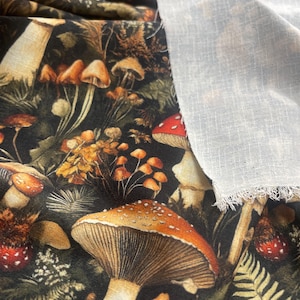 Dark woodland mushroom fabric shown next to a piece of plain white woven fabric.