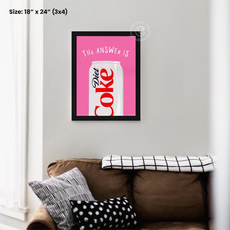 May include: A framed print with a pink background and a white can of Diet Coke. The text "THE ANSWER IS" is written in black above the can.