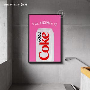 May include: A pink poster with black framing featuring a can of Diet Coke with the text "THE ANSWER IS" above it. The poster measures 24 inches by 36 inches.