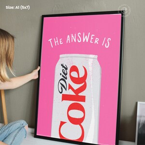 May include: A pink background with a white can of Diet Coke. The text "THE ANSWER IS" is written in white above the can.