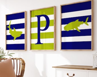 May include: Three framed prints with a nautical theme. The prints feature a blue and white striped background with a green shark silhouette, a green and white striped background with a blue letter "P", and a blue and white striped background with a green shark silhouette.