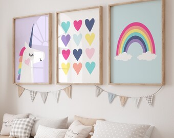 May include: Three framed prints with a rainbow, a unicorn, and a pattern of colorful hearts. The prints are hung on a white wall above a wooden bench with pillows.