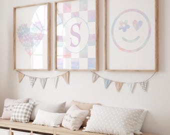 May include: Three framed pastel-colored prints with a heart, a letter S, and a smiley face. The prints are hanging on a white wall above a wooden bench with gray and white patterned pillows.