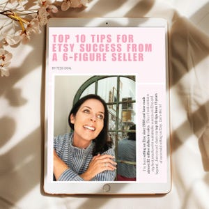 May include: A digital tablet displays a pink screen with the text "TOP 10 TIPS FOR ETSY SUCCESS FROM A 6-FIGURE SELLER" and a photo of a woman. The text is accompanied by the author's name, Tess Deal, and a brief description.