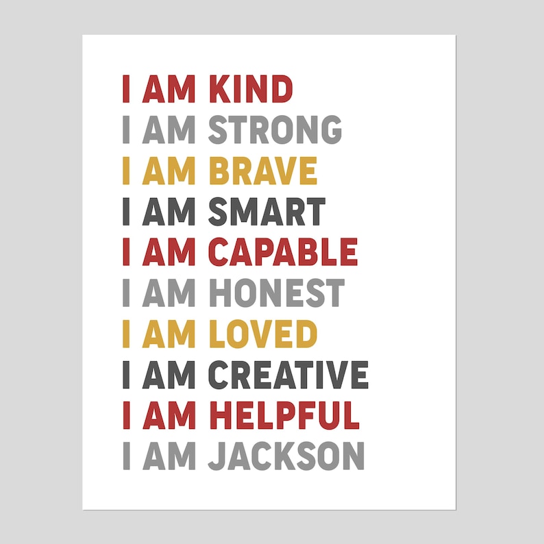 May include: A white background with the text "I AM" in red, gray, gold, and black. The text includes the words "KIND, STRONG, BRAVE, SMART, CAPABLE, HONEST, LOVED, CREATIVE, HELPFUL, JACKSON".