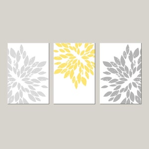 May include: Three abstract art prints with a white background and a gray and yellow floral design. The prints are arranged in a row.