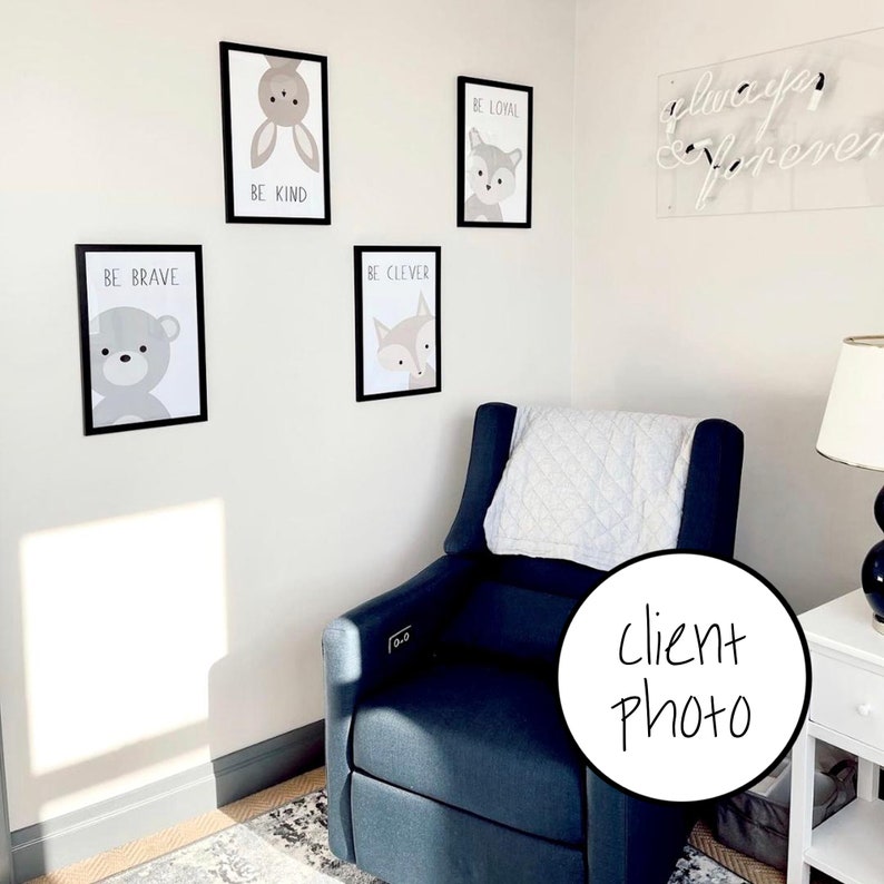 May include: A nursery room with a blue armchair, a white throw blanket, and a white wall with framed animal prints. The prints feature a bear, a fox, a bunny, and a wolf. The text on the prints reads "Be Brave", "Be Clever", "Be Kind", and "Be Loyal". A neon sign on the wall reads "Always & Forever".