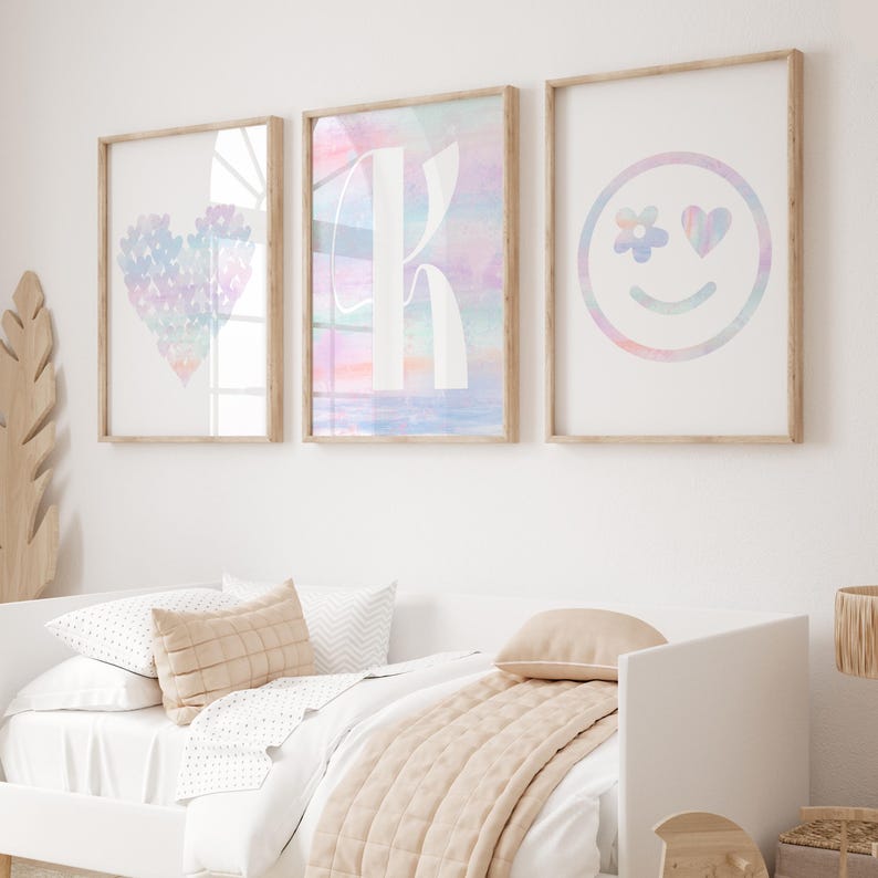 May include: Three framed prints with pastel watercolor designs. The first print features a heart shape with a rainbow pattern. The second print features the letter K with a rainbow pattern. The third print features a smiley face with a rainbow pattern and a heart for one eye.