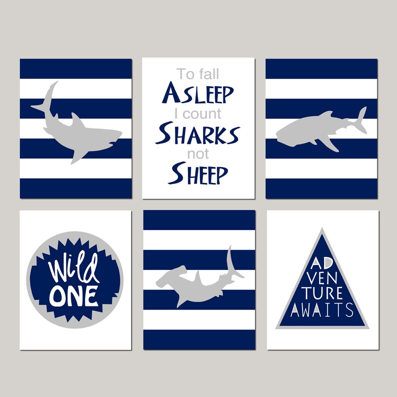 May include: Set of six printable nursery art prints featuring a shark theme. The prints feature blue and white stripes, a shark silhouette, and text that says "To fall asleep I count sharks not sheep", "Wild One", and "Adventure Awaits".