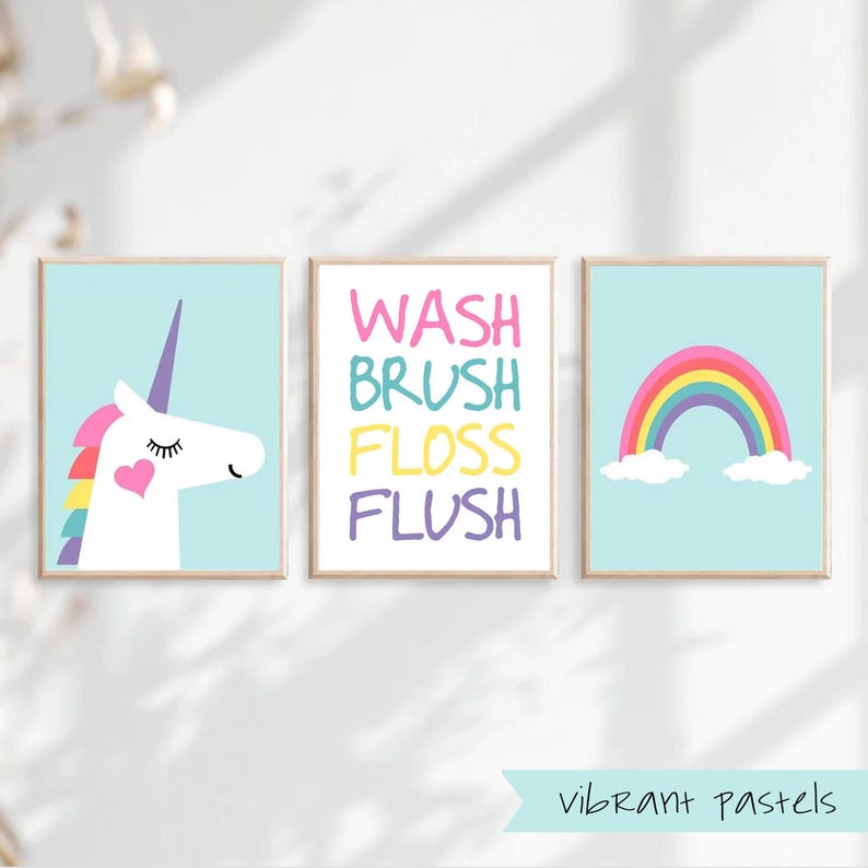 May include: Three bathroom wall art prints with a pastel color scheme. The first print features a white unicorn with a rainbow mane and a pink heart on its chest. The second print says "WASH BRUSH FLOSS FLUSH" in colorful letters. The third print features a rainbow with clouds on a light blue background. The text "vibrant pastels" is at the bottom of the image.