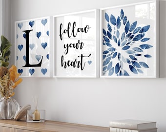 Könnte beinhalten: Drei gerahmte Drucke mit weißem Hintergrund. Der linke Druck zeigt ein blaues und weißes Muster aus Herzen mit dem Buchstaben L in der Mitte. Der mittlere Druck zeigt den Text "follow your heart" in Schwarz. Der rechte Druck zeigt ein blaues Aquarelldesign aus Blättern.