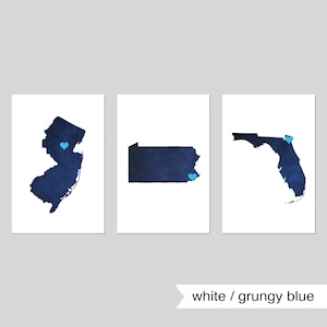 May include: Three printable wall art prints featuring the outlines of New Jersey, Pennsylvania, and Florida. Each state is filled with a dark blue watercolor-like design and has a small blue heart in the center.