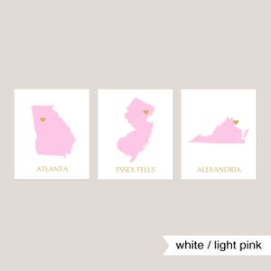 May include: Three printable maps with pink outlines of Georgia, New Jersey, and Virginia. Each map has a gold heart marking a specific location. The text below each map reads "Atlanta", "Essex Fells", and "Alexandria". The text "white / light pink" appears below the maps.