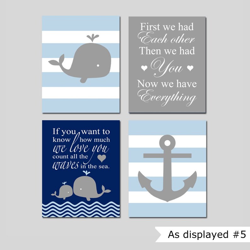 Op de afbeelding: Set van vier nautisch gethematiseerde kinderkamerprints met blauwe en grijze strepen. De prints bevatten een walvis, een anker en tekst die luidt "Als je wilt weten hoeveel we van je houden, tel dan alle golven in de zee." en "Eerst hadden we elkaar, toen hadden we jou, nu hebben we alles."