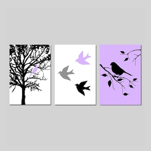 Puede incluir: Un conjunto de tres impresiones de arte de pared con siluetas negras de p&aacute;jaros y ramas sobre un fondo blanco, gris y lavanda.