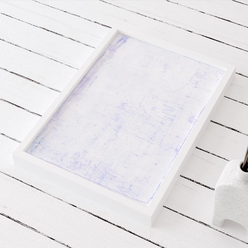 May include: A white picture frame with a light purple background. The frame is sitting on a white wooden surface.