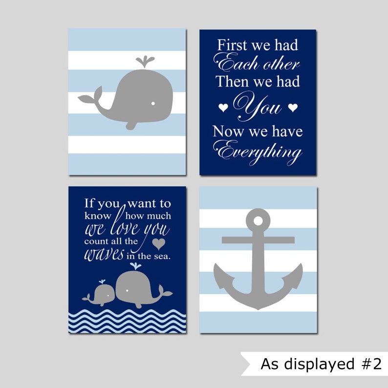 Op de afbeelding: Set van vier navyblauwe en lichtblauwe gestreepte prints met walvis- en ankerillustraties. De prints bevatten de tekst "Als je wilt weten hoeveel we van je houden, tel dan alle golven in de zee." en "Eerst hadden we elkaar, toen hadden we jou, nu hebben we alles."