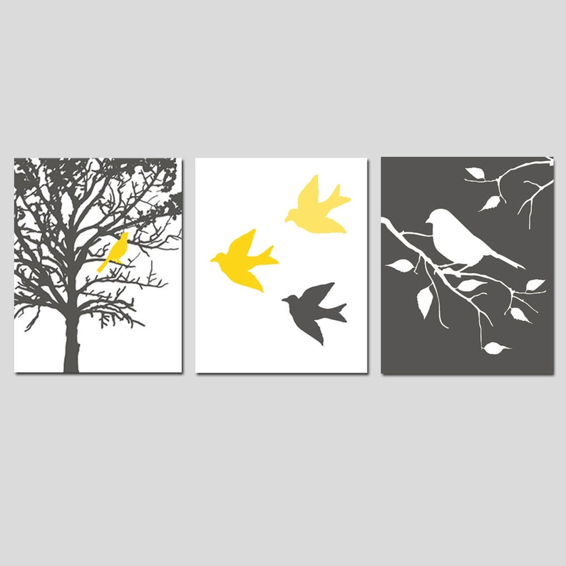 May include: A set of three wall art prints featuring a black and white silhouette of a tree with a yellow bird, three yellow birds flying, and a white bird on a branch. The prints are on a white background.