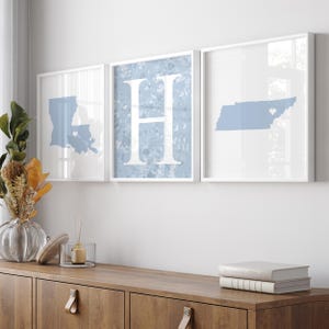May include: Three framed wall art pieces. The first features a light blue outline of Louisiana with a heart. The second displays a large white letter "H" on a blue background. The third shows a light blue outline of Tennessee with a heart.