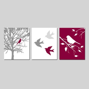 Puede incluir: Conjunto de tres impresiones de arte de pared con un &aacute;rbol gris con un p&aacute;jaro rojo, tres p&aacute;jaros grises en vuelo y un p&aacute;jaro blanco posado en una rama sobre un fondo burdeos.