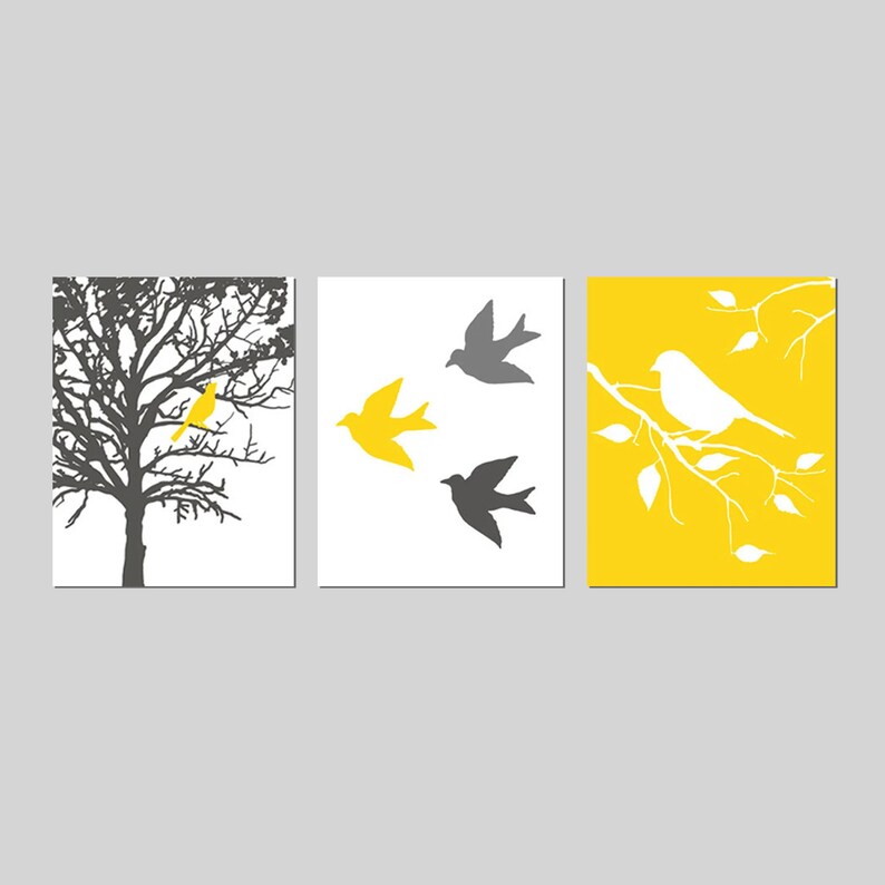Puede incluir: Un conjunto de tres impresiones de arte de pared con un esquema de color amarillo y gris. La primera impresi&oacute;n muestra una silueta de un &aacute;rbol con un p&aacute;jaro amarillo posado en una rama. La segunda impresi&oacute;n muestra tres p&aacute;jaros en vuelo, dos grises y uno amarillo. La tercera impresi&oacute;n muestra un fondo amarillo con una rama blanca y un p&aacute;jaro blanco posado en ella.