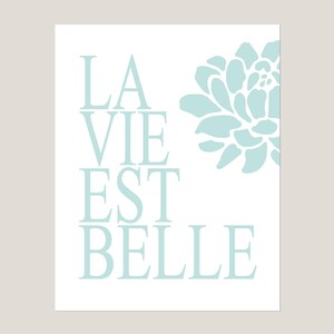 Puede incluir: Una impresi&oacute;n azul claro con el texto "LA VIE EST BELLE" y una flor azul estilizada.