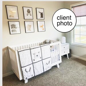 May include: White crib with a white and gray animal print quilt. The crib is in a nursery with a white wall and framed animal prints.