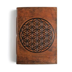 May include: A brown leather journal with a black embossed flower of life design.