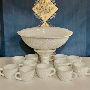 May include: A white milk glass punch bowl with a pedestal base and 10 matching cups. The bowl and cups have a raised, embossed design.