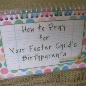 May include: A small, spiral-bound book with a colorful polka dot cover. The title reads "How to Pray for Your Foster Child's Birthparents".