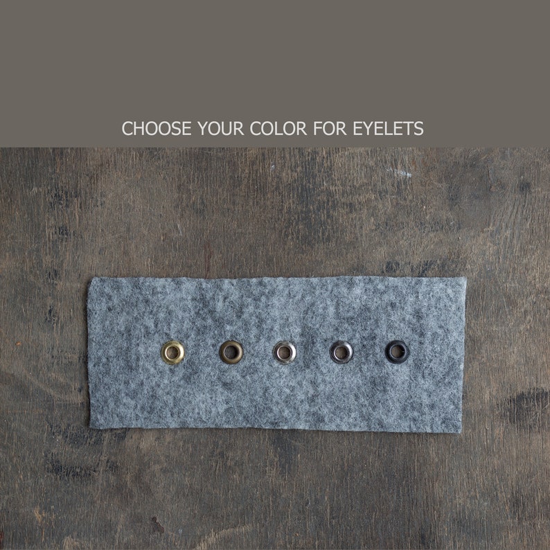 May include: A close-up of five metal eyelets in different colors on a gray felt swatch. The colors are gold, silver, nickel, black, and antique brass.  Choose your color for eyelets.