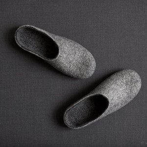 May include: A pair of gray felt slippers. The slippers are soft and comfortable, perfect for wearing around the house.
