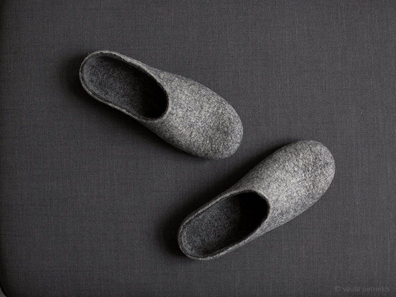 May include: A pair of gray felt slippers. The slippers are soft and comfortable, perfect for wearing around the house.
