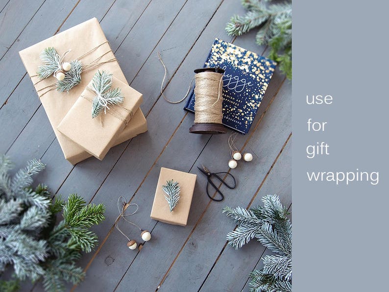 May include: Two brown gift boxes wrapped with twine and decorated with sprigs of greenery and white beads. A third box is partially visible in the background. A spool of twine and a pair of scissors are also visible. The text "use for gift wrapping" is visible in the background.