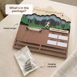 May include: A wooden medal hanger featuring a layered mountain and forest landscape, a metal clipboard, and a runner silhouette. It includes the text "What's in the package?", "CHRISTOPHER JOHNSON", "5K", "10K", "HALF", "FULL", and a quote by Dean Karnazes.
