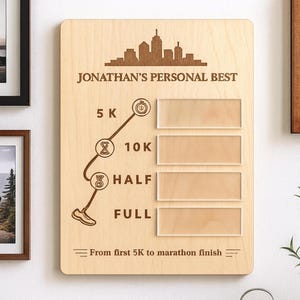 May include: Wooden plaque with the text "JONATHAN'S PERSONAL BEST" and a city skyline silhouette. The plaque features spaces for 5K, 10K, Half, and Full marathon times, with the text "From first 5K to marathon finish."