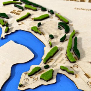 May include: A wooden golf course map featuring raised green areas representing the greens and fairways. Blue paint indicates water features. The map includes numbered holes and architectural details.