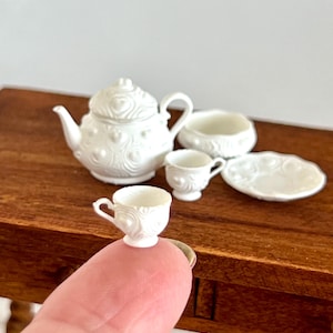 Può includere: Servizio da tè in miniatura bianco con teiera, lattiera, zuccheriera, due tazze e piattini e un piatto. Il set è decorato con un motivo a cuore in rilievo.