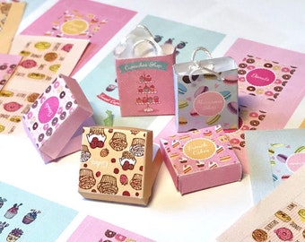 May include: A collection of miniature paper boxes and shopping bags with various bakery themes. The boxes are decorated with donuts, cupcakes, macarons, and French cakes. The bags have the words "Cupcakes Shop", "Macarons Shop", and "Donuts" printed on them.