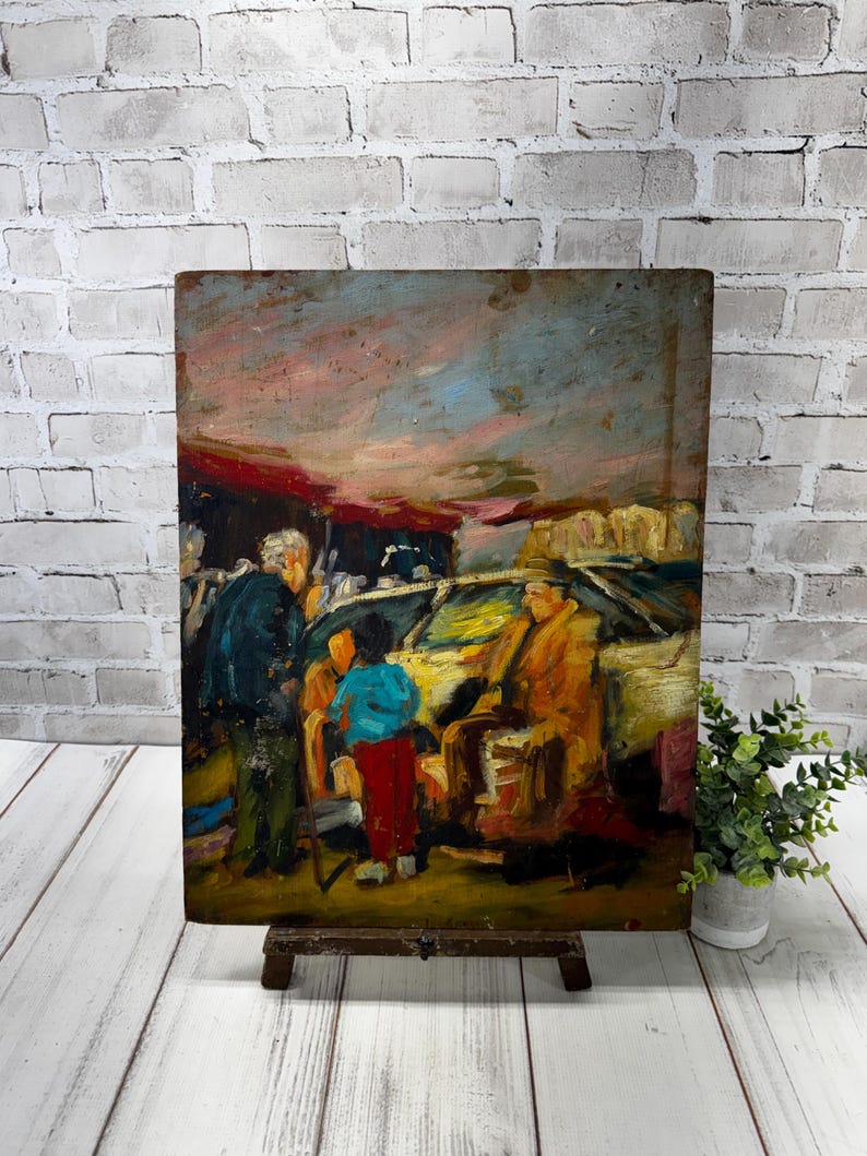 May include: An original oil painting on a wooden panel, depicting a street scene with figures. The artwork features a palette of warm colours, including orange, yellow, and blue, with visible brushstrokes. The painting is displayed on a small wooden easel.