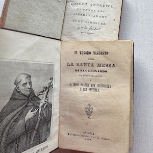 May include: Two antique books with aged, off-white pages. The top book title page reads Aventures de Joseph Andrews et de son ami Abraham Adams. The bottom book features an engraving of a monk holding a crucifix and the title Il Tesoro Nascosto.