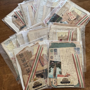 May include: A collection of multiple clear plastic bags filled with assorted vintage paper ephemera, including handwritten letters, ledger pages, postcards, playing cards, and numbered tickets, each accented with a decorative red and green ribbon.