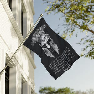 May include: A black rectangular flag featuring a white graphic of a Spartan helmet with Roman numerals XII and II on the eye slits. Below the helmet is the text: DO NOT CONFORM TO THE PATTERN OF THIS WORLD, BUT BE TRANSFORMED BY THE RENEWING OF YOUR MIND.