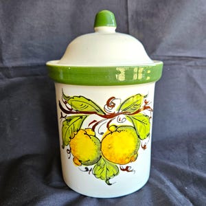 May include: A white ceramic mug with a black handle and the text "But First, Coffee" in a handwritten style. The mug is on a white surface. The mug is approximately 4 inches tall.