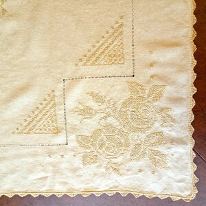 May include: A light beige rectangular textile featuring intricate tone-on-tone embroidery of floral rose motifs and geometric triangular patterns. The fabric is finished with a delicate scalloped crochet lace border along the outer edge.