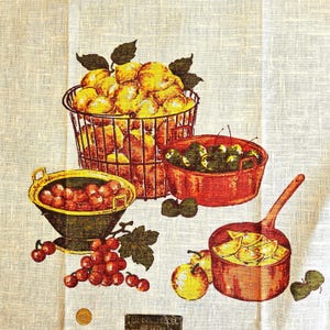May include: A white linen fabric featuring a printed illustration of a wire basket filled with yellow peaches, a red bowl of green cherries, a yellow bowl of red cherries, a cluster of red grapes, and a copper pan containing sliced yellow apples.