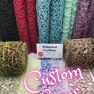 May include: Multiple rolls of decorative mesh ribbon in black, red, teal, light green, purple, and brown. A white rectangular sign in the center displays the text Whimzical CreStions and Custom Sizes in pink script font over the mesh material.