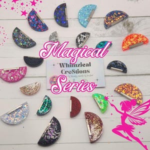 May include: A collection of glittery, half-circle shaped hair clips in various colors, including blue, pink, and gold. The clips are arranged around a card that reads "Magical Series" and "Whimzical Creations". A pink fairy illustration is also present.