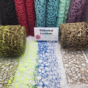 May include: A variety of colorful, open-weave decorative mesh rolls in black, red, teal, mint green, and purple. Several rolls are standing upright, while others are laid flat. The image also shows a business card with the text "Whimzieal Creations".