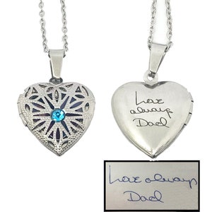 May include: Silver heart-shaped locket necklace with a blue crystal in the center and an inscription that reads "Love always Dad".
